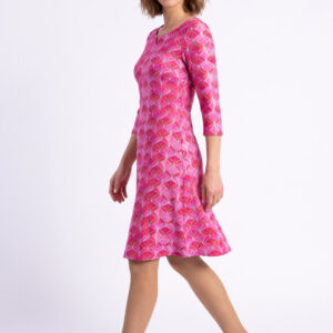 Eine Frau trägt unser Herbstkleid Audrey in pinkem Muster. Sie trägt dazu braune Wildlederpumps.